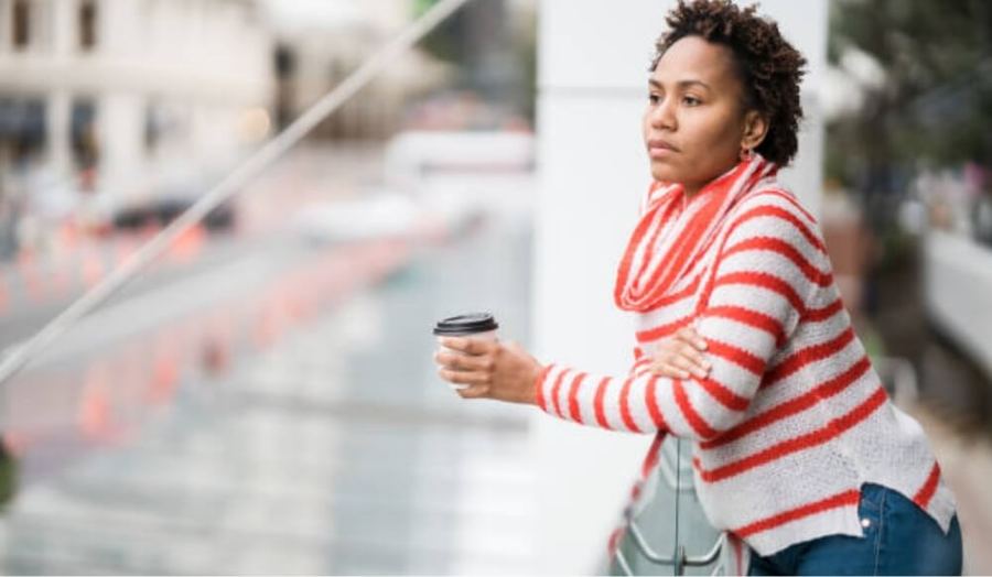A woman holding a coffee cup, looking thoughtful