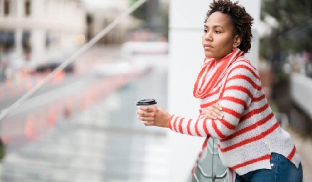 A woman holding a coffee cup, looking thoughtful