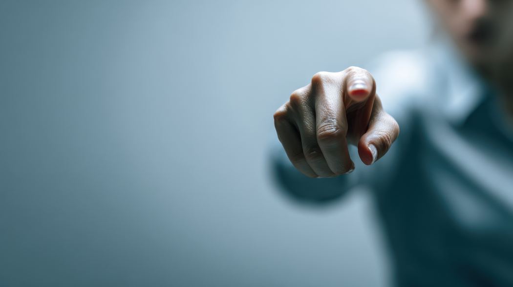 Blurred person pointing an accusing finger towards the camera